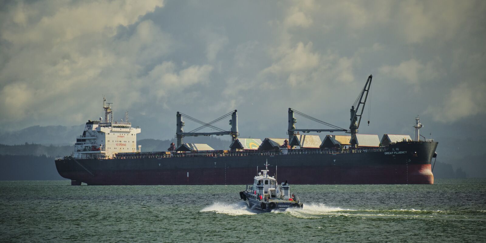 A pilot boat speeds out to a loaded freighter on the Columbia River.